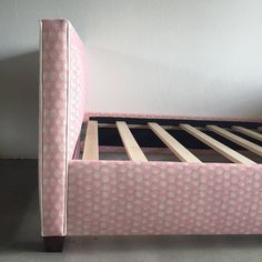 a pink bed frame with wooden slats