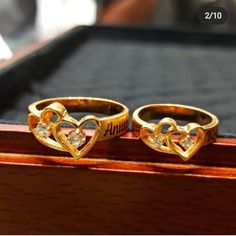 two gold rings with hearts on them sitting on top of a wooden box