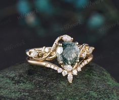 a green and white diamond ring sitting on top of a rock