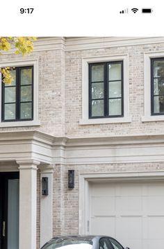 a white car parked in front of a house with two garage doors on each side