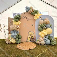 a winnie the pooh balloon arch is set up for a baby shower