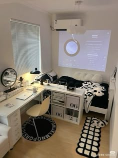 a bedroom with a bed, desk and chair in front of a projector screen