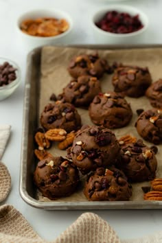 chocolate cookies with nuts and dried cranberries on a baking sheet