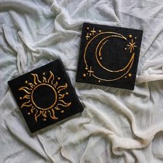 two black and gold square coasters sitting on top of a bed