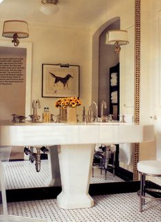 a white pedestal sink in a bathroom with mirrors on the wall and pictures above it