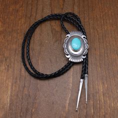 Beautiful sterling silver and turquoise bolo tie. The concho style oval is 2 1/2" tall x 1 3/4" wide. The turquoise is 24 mm tall. The cord and tips are 43" long. The back is stamped Sterling. There is no signature. The work is Navajo style. The domed center is accented with the turquoise stone and stamp work. The edge has cut work and stamp work. It is in good condition. Thank you for shopping in our store. Please let us know if you have questions. BOLO-1576K k *The color you see on your screen Southwestern Turquoise Lariat Bolo Tie, Artisan Turquoise Bolo Ties With Concho, Southwestern Concho Bolo Tie For Ranch, Southwestern Bolo Ties With Concho, Southwestern Bolo Ties With Concho For Ranch, Southwestern Turquoise Bolo Ties For Western-themed Events, Southwestern Turquoise Bolo Tie For Western-themed Events, Southwestern Adjustable Turquoise Bolo Ties, Vintage Turquoise Bolo Ties For Rodeo