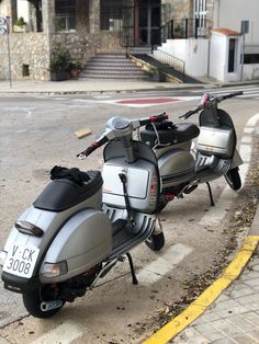 two motor scooters parked on the side of the road in front of a building