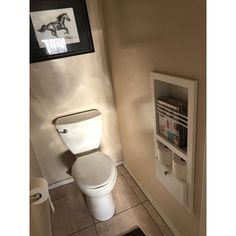 a white toilet sitting in a bathroom next to a wall mounted magazine rack with magazines on it