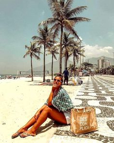 a woman sitting on the beach next to palm trees