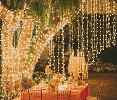 an outdoor dining area with lights strung from the trees and tables set for dinner outside