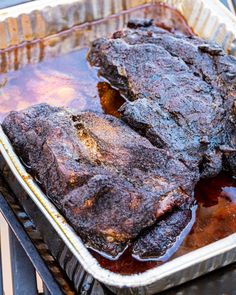 two pieces of meat sitting on top of a pan covered in bbq barbecue sauce