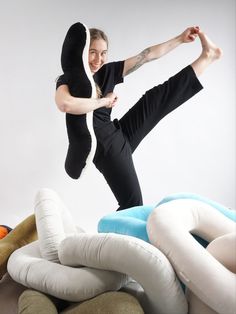 a woman is jumping in the air surrounded by pillows