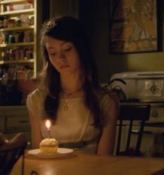 a woman sitting at a table with a cupcake in front of her