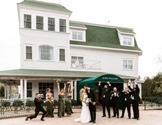 a group of people that are standing in front of a white building with green roof