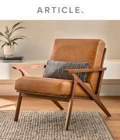 a brown leather chair sitting on top of a wooden floor next to a potted plant