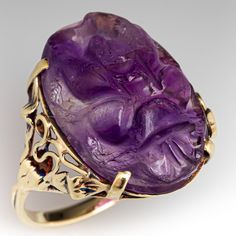 This vintage ring is centered with a four-prong set carved amethyst oval cabochon weighing 10.45 carats. The shoulders are accented with an open vine and leaf design. The ring measures 20.8mm at the top, rises 6.6mm above the finger, tapering to 1.9mm wide and 1.1mm thick at the base of the shank.  The ring is crafted in 14k yellow gold and is currently a size 8.75. Collectible Oval Cabochon Amethyst Ring, Formal Cabochon Amethyst Ring Fine Jewelry, Luxury Amethyst Cabochon Ring, Luxury Purple Cabochon Amethyst Ring, Luxury Purple Amethyst Cabochon Ring, Antique Oval Amethyst Ring, Antique Oval Purple Amethyst Ring, Vintage Amethyst Rings With Polished Finish, Vintage Amethyst Jewelry With Polished Finish