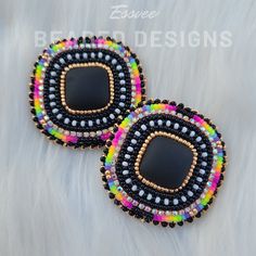 two black and multicolored beaded earrings on top of a white fur surface