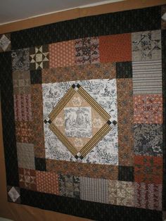 a quilt hanging on the wall in a room with white walls and brown trimmings