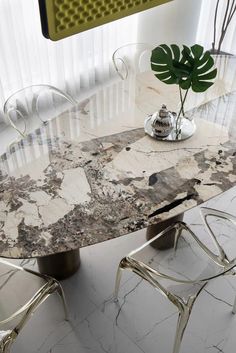 a marble dining table with four chairs and a potted plant in the center on top