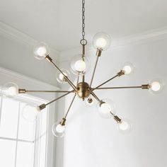 a chandelier hanging from the ceiling in a room with white walls and windows