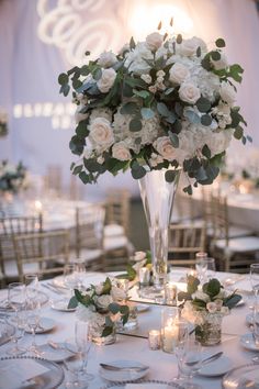 a vase filled with white flowers sitting on top of a table covered in silverware