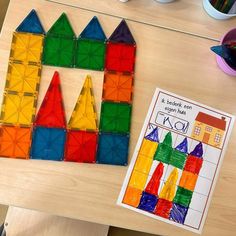 a wooden table topped with lots of different colored plastic blocks next to a piece of paper