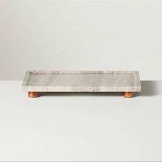 a marble tray with wooden legs on a white surface