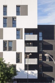 an apartment building with many windows and balconies on the front, along side a street light