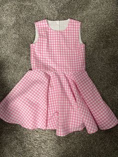 Beautiful  Barbie inspired pink gingham checked twirl dress..  The gingham fabric is Robert Kaufman  cotton.  The sleeveless dress has a fully lined bodice.  The back closes with kam Plastic  snaps.  The dress has a full circle twirl for that little dancer.    I would be happy to make this dress in other colors or fabric.  available in sizes 12 months to size 8  Measurements will be in the photo section Playful Gingham Dress With Ruffles, Playful Gingham Dress For Spring, Spring Playful Gingham Dress, Plaid Ruffled Dresses For Garden Party, Playful Sleeveless Gingham Dress, Sleeveless Gingham Dress With Ruffles, Cute Sleeveless Plaid Dress, Cute Plaid Sleeveless Dress, Cute Gingham Dresses For Garden Party