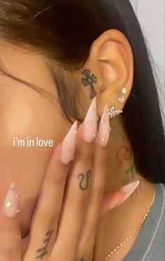 a woman with tattoos and piercings on her ear is covering her face while she has her hand under her ear