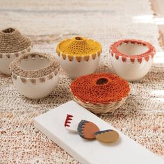 several crocheted baskets and bowls on a table with an object next to them