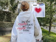 a woman wearing a white hoodie with the words in the right place at the time printed on it