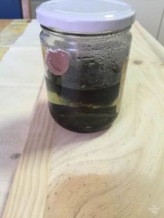 a jar filled with liquid sitting on top of a wooden table