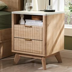 a wooden night stand with two drawers and a wine glass on the side table next to it