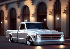 a white pickup truck parked in front of a building at night with its lights on