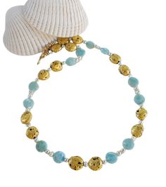 Beloved Necklace in 23-Karat Gold Leaf on Lava Stone, Larimar, and Freshwater Pearls This necklace features a hand-gilded black lava stone adorned with larimar, freshwater pearls, and a 14-Karat gold-filled toggle clasp. The larimar stones showcase a captivating blue color with white veining reminiscent of clouds against a clear blue sky. The necklace measures 21.5" (54.61cm) and comes with a gold designer signature tag. Larimar is known for promoting relaxation and serenity. The necklace will b Elegant Round Amazonite Necklace, Elegant Gold Amazonite Necklace, Larimar Gemstone Beads Round Jewelry, Round Larimar Gemstone Beads Jewelry, Larimar Gemstone Beads Necklace As Gift, Larimar Gemstone Beads Necklace For Gift, Larimar Gemstone Bead Necklaces For Gifts, Larimar Beaded Jewelry For Gifts, Larimar Round Beads Jewelry For Gifts