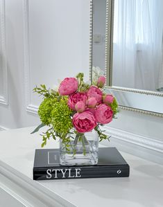 a vase filled with pink flowers sitting on top of a table next to a mirror