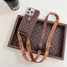 two louis vuitton phone cases are sitting in a box next to a coffee cup