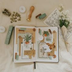 an open book with some flowers and other items on the table next to each other