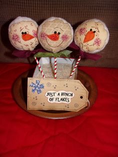 three snowmen sitting on top of a wooden tray with candy canes in it