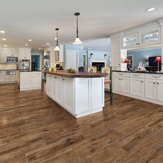 a large kitchen with wood floors and white cabinets