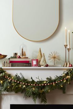 a mantle with christmas decorations and candles on it