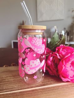 a pink mason jar with a straw in it next to flowers