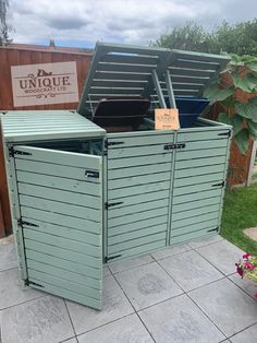 two large metal storage bins sitting next to each other on a tiled floor in front of a wooden fence