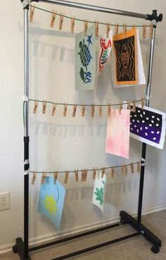 clothes are hung on the clothes line with pegs in front of them and some pictures hanging from clips to dry