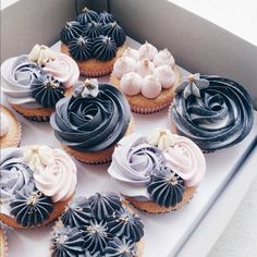 twelve cupcakes in a box with frosting and flowers on top are shown