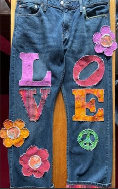 an old pair of jeans with the word love written on it and flowers painted on them