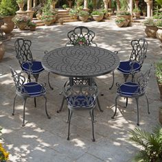 an outdoor dining table and chairs set in the middle of a patio with potted plants