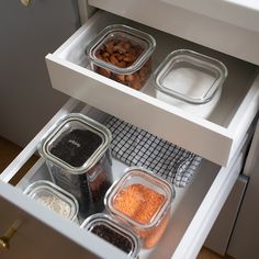 an open drawer in a kitchen filled with spices and seasoning containers on the bottom shelf