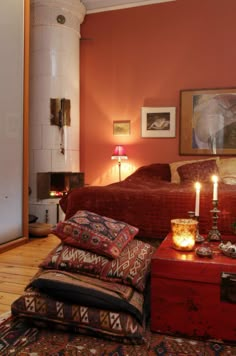 a room with a bed, rugs and candles on the table in front of it